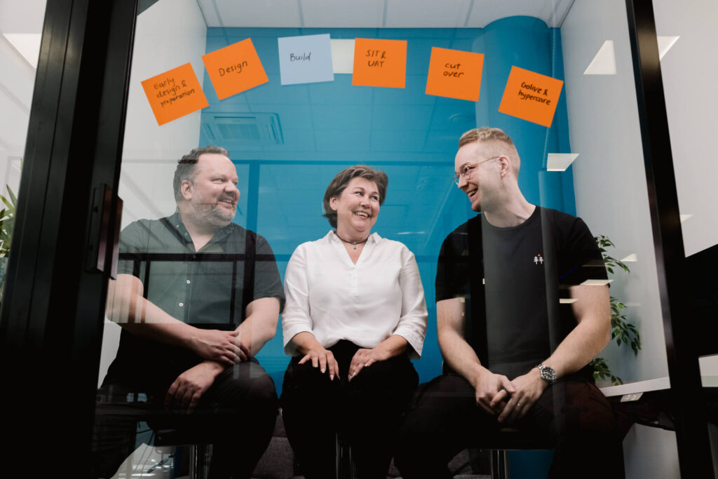 Tiia Vainionpää, Patrik Koso ja Ari Varjonen lasineukkarissa, jonka seinällä muistilapuilla projektin vaiheet.