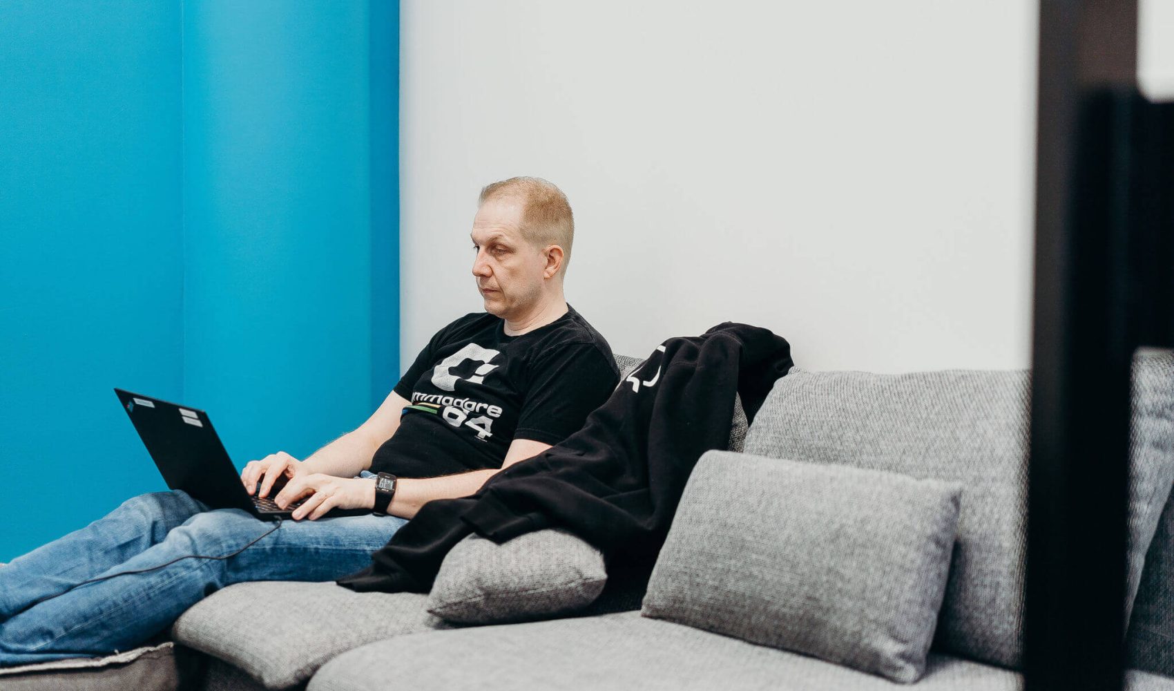 Qalmarin ohjelmistokehittäjä Jani Mellin työskentelemässä sohvalla, läppäri sylissään.
